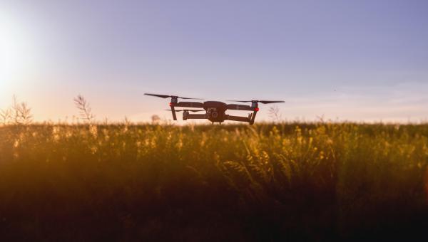 A quadcopter drone flying over agriculture land