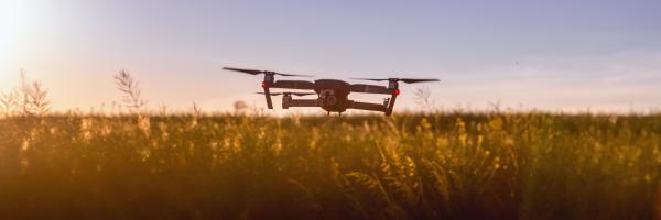 A quadcopter drone flying over agriculture land